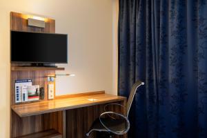 不莱梅不来梅机场快捷假日酒店的客房设有书桌、电视和椅子