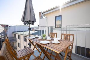 萨勒河畔哈雷Ko-Living - Captain's Suite - Altstadt - mit Küche, Smart TV & Balkon - 6P的阳台上配有一张带椅子和遮阳伞的木桌