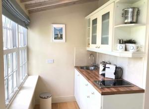 金塞尔Coastal Chic waterfront studio的厨房配有白色橱柜、水槽和窗户。