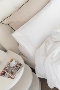 巴塞罗那El Palauet Royal Suites的一张带白色床单的床和一张桌子上的杂志
