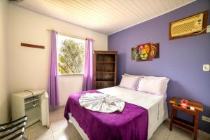 帕拉蒂Pousada Cantinho do Sossego Paraty的一间卧室设有紫色的墙壁和一张带紫色毯子的床。