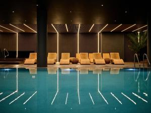 克拉科夫AC Hotel by Marriott Krakow的一组椅子坐在游泳池旁