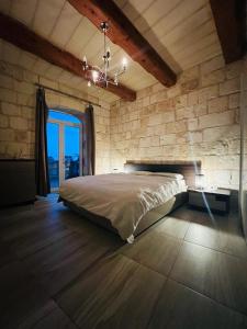 SiġġiewiId-dar Taz-zija Holiday Home including pool & garden的一间卧室设有一张床和石墙