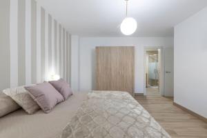 格拉纳达Neptuno Deluxe的一间白色卧室,配有一张床和一个走廊
