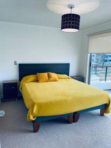 埃尔塔波Amplio depto en el Tabo 6 personas的一间卧室配有一张带黄色毯子的大床