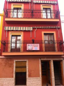 梅里达塞奈罗酒店的一座红色的建筑,设有阳台,上面有标志