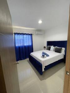 圣地亚哥洛斯卡巴Mountain View Cibao的一间卧室配有床和蓝色窗帘