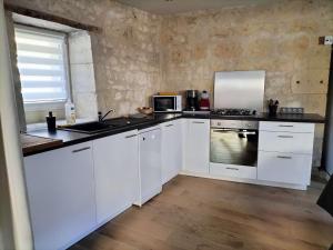 BenaisGite du four à pain的厨房配有白色橱柜和炉灶烤箱。