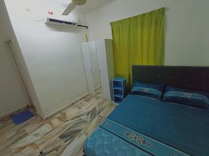 加央Simple Beseri Homestay的一间卧室配有蓝色的床和绿色窗帘