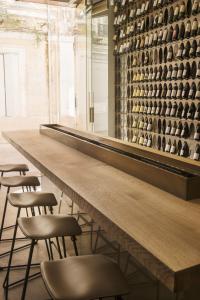 圣雷米普罗旺斯Hôtel de Tourrel, Saint Rémy de Provence, a Member of Design Hotels的一张带凳子的长桌和一堵葡萄酒瓶