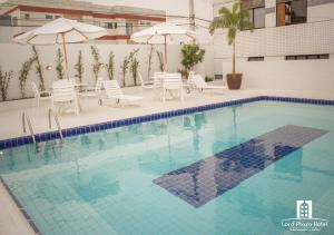 泰谢拉迪弗雷塔斯Lord Plaza Hotel的一个带桌椅和遮阳伞的游泳池