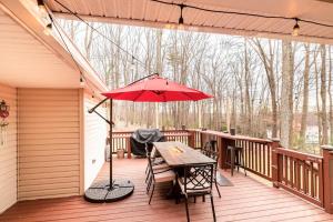 东斯特劳兹堡Blue Mountain Lake Pocono House的平台上设有带桌子和遮阳伞的天井。