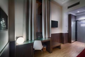 罗马拉加内利酒店的客房设有一张桌子、一把椅子和一台电视