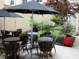 巴黎New Hotel Saint Lazare的一组桌子和椅子,放在伞下
