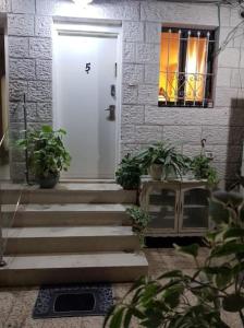 耶路撒冷Lovely 2 bedroom unit, Shivtey Israel, Jerusalem的白色的前门,有盆栽植物的房子