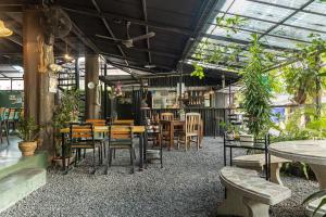 Ban Na WeBlockhouse Hostel的一间设有桌椅的餐厅,种植了植物