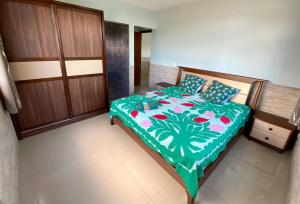OpoaTaina - Terrasse - Bord de mer -的一间卧室配有一张带绿色和白色棉被的床