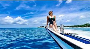 吉利阿尔Manusia Dunia Green Lodge的坐在海洋上船尾部的女人