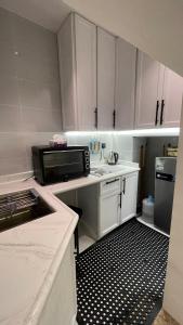 阿哈达بيت الجبل عوائل فقط的厨房配有白色橱柜和黑白瓷砖地板。