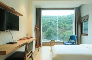黄山风景区茶民宿（黄山景区免费接送）的酒店客房设有一张书桌和一个大窗户。