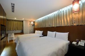 台北华大旅店-南西馆的配有白色床单的酒店客房内的两张床