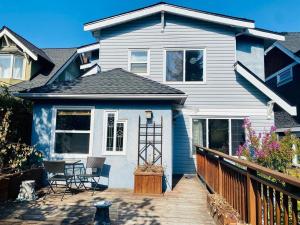 温哥华Cozy Dunbar 3 Beds Home w/ Views的蓝色的房子,上面有带椅子的甲板