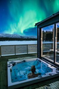 阿尔塔Flatmoen Natur Lodge的被置于热水浴缸中的,在北极光下的人