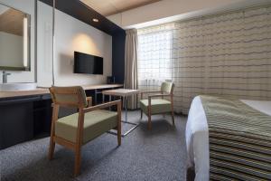 广岛Hotel Vista Hiroshima的酒店客房,配有一张床、一张桌子和椅子