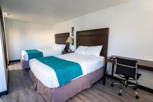 肯纳威克Kennewick Inn & Suites Tri Cities的酒店客房 - 带两张床、一张桌子和一把椅子