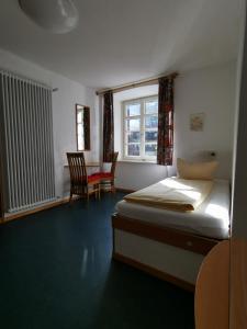 托特莫斯Europäisches Gäste- und Seminarhaus的卧室配有一张床和一张桌子及椅子