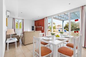 卡兰博希Villas Calan Bosch Ona的用餐室以及带白色桌椅的起居室。