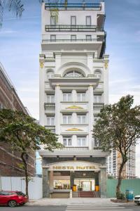 河内Nesta Boutique Hotel Hanoi的前面有一辆红色汽车,高大的白色建筑