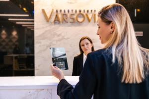 华沙巴索维亚卡斯帕莎卡公寓酒店的一位在镜子前看手机的女人
