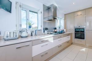 Bodelwyddan"Woodlands" by Greenstay Serviced Accommodation - Luxury 3 Bed Cottage In North Wales With Stunning Countryside Views & Parking - Close To Glan Clwyd Hospital - The Perfect Choice for Contractors, Business Travellers, Families and Groups的厨房配有白色橱柜和炉灶烤箱。