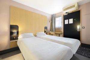 佩皮尼昂B&B HOTEL Perpignan Sud Porte d'Espagne的配有白色床单的酒店客房内的两张床