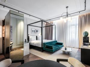 维也纳The Amauris Vienna - Relais & Châteaux的酒店客房,设有一张床铺和一张绿色沙发