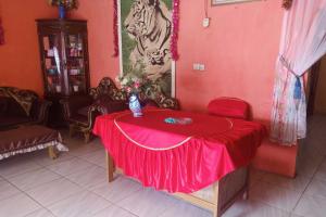 占碑市EXPRESS O 92251 Jaya Kusuma Homestay的一间设有一张桌子的房间,配有红色桌布