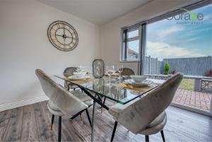 达德利3 Bedroom Luxe Living for Contractors and Families by Coraxe Short Stays的一间用餐室,配有玻璃桌、椅子和时钟