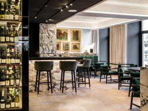 维也纳The Amauris Vienna - Relais & Châteaux的一间酒吧,配有绿色椅子和瓶装葡萄酒