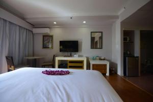 塔穆宁Days Inn Guam - Tamuning的卧室配有白色的床,床上布满了紫色的鲜花