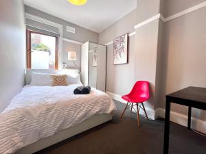 悉尼Coco’s Abode的一间卧室配有一张床、一张桌子和一把红色椅子