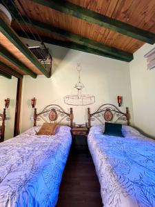 夸科斯德尤斯特Casa Rural Juan de Austria的一间卧室配有两张带蓝色床单和吊灯的床。