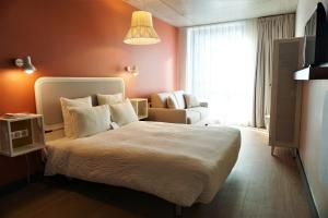 楠泰尔OKKO Hotels Paris La Défense的卧室配有床、椅子和窗户。