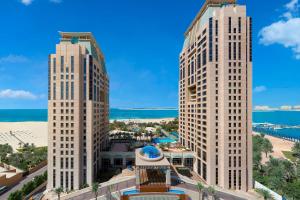 迪拜傲途格精选酒店旗下哈布图尔格兰德度假村的两座高大的白色建筑,毗邻大海