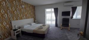 卡什泰拉Hotel Aqua - Guest Rooms & Suites Kaštela的配有一张床和一把椅子的酒店客房