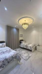 吉达luxury apartment - Prince majed park的一间卧室配有两张床和吊灯。