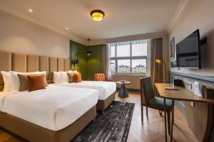 斯利那加Sarovar Portico Srinagar的酒店客房配有两张床和一张书桌