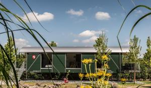 斯塔德特罗恩LokoMotel-Waggon, Luxus Appartment im Eisenbahnwaggon的花园里的绿色大篷车,带灰色屋顶