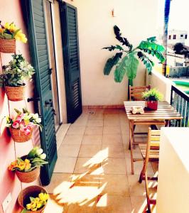 托里德欧索HOLLY CASA VACANZE TORRE DELL'ORSO的阳台配有桌子、盆栽植物和门
