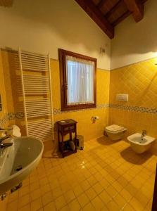 斯特拉Bed and Breakfast Ca’ Pisani的黄色瓷砖浴室设有水槽和卫生间